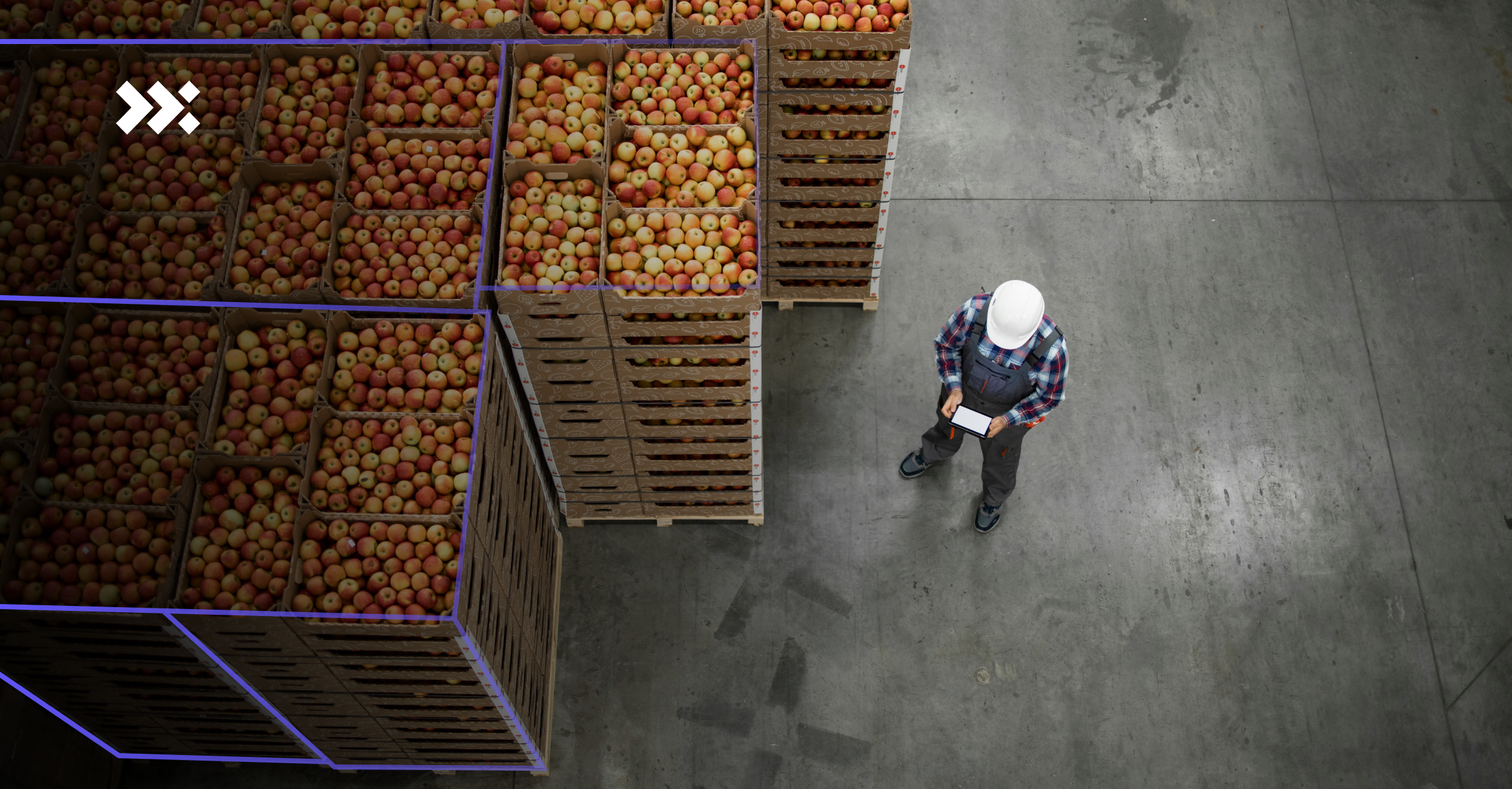 A logistics worker stands next to the boxes filled with fruits